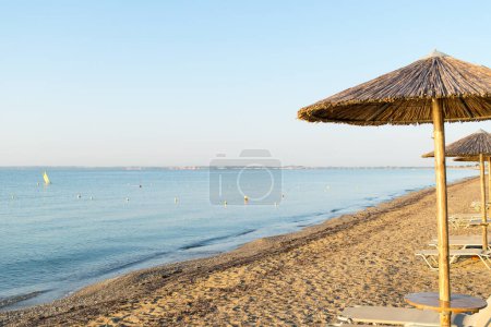 Foto de View of wooden umbrellas and sun loungers on a Mediterranean beach - Imagen libre de derechos