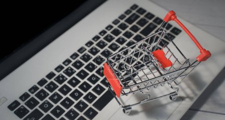 Photo for Shopping online. Trolley in front laptop keyboard. Business retail shop store marketing online. Shipping service technology, order check out website, home delivery package, client buying on e-commerce - Royalty Free Image