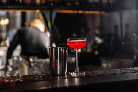 Foto de Red cocktail and shaker on the bar. Bar nightlife atmosphere. - Imagen libre de derechos