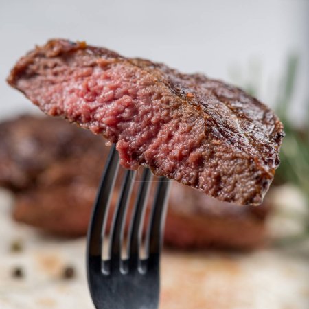 Piece of medium-roasted steak on a fork close-up