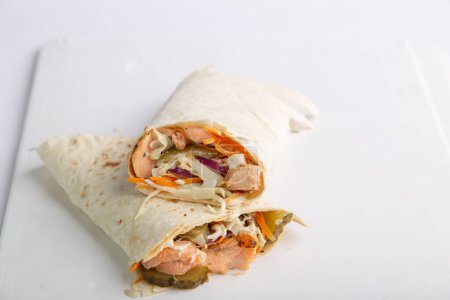Téléchargez les photos : Rouleau de pita au saumon et légumes. Shawarma en pain pita farci aux légumes et au poisson - en image libre de droit