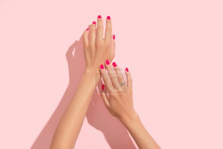 Photo for Womans hands with pink nail design. Manicure, pedicure beauty salon concept. Trendy color. Deep long shadows. - Royalty Free Image