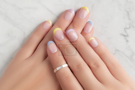 Beautiful womans hands with spring summer nail design on marble gray background. Manicure, pedicure beauty salon concept