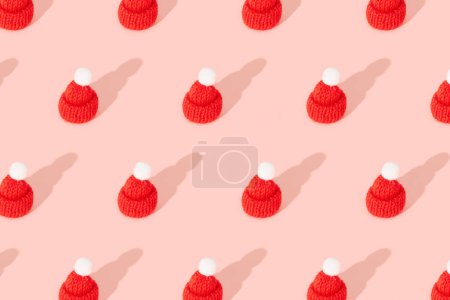 Téléchargez les photos : Jouet mini chapeau sur un fond rose avec de longues ombres. Vêtements concept de vente d'hiver. papier peint de Noël carte postale. - en image libre de droit