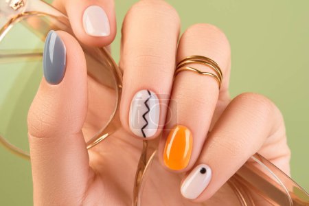 Close up womans hands with trendy minimal manicure on green background. Spring summer nail design. Beauty salon concept.