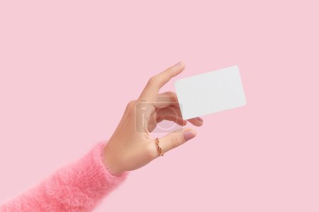 Photo for Womans hand touch a white blank business card that floats on a pink background. Flat lay of a simple business card with top view. Work and Education - Royalty Free Image
