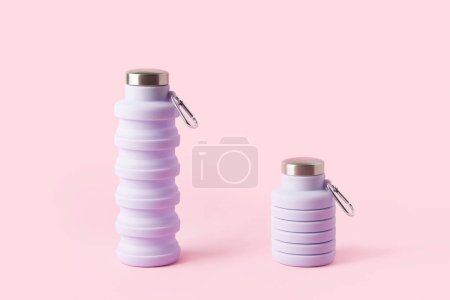 Collapsible reusable lilac water bottle on pink background. Plastic-free packaging. Sustainability, eco-friendly lifestyle