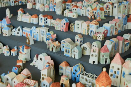 Assortment of hand-painted mini houses on shelves, in various colors and designs. Local market