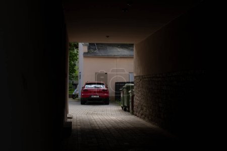 Photo for Arch in a typical post-soviet apartment building in Tallinn city center (Estonian - Kesklinn). View of a red Porsche Macan S parked in a quiet courtyard. - Royalty Free Image