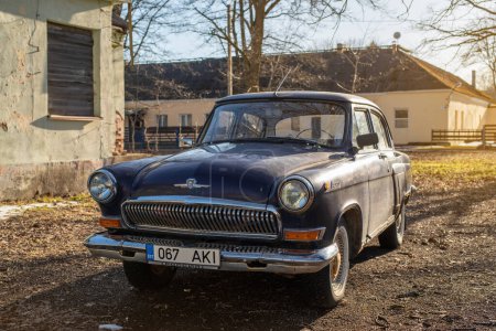 Téléchargez les photos : GAZ 21 bleu foncé stationné sur un chemin de gravier. Classique voiture vintage Volga. - en image libre de droit