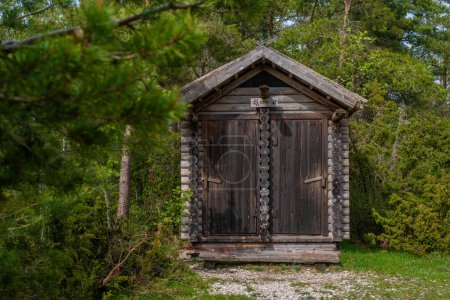Wooden public toilet in the Estonian forest near the public rest and barbeque RMK area on a cloudy summer day. Kassari, Saaremaa, Estonia