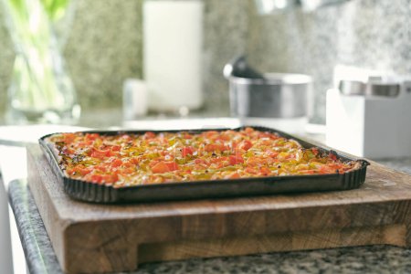 Téléchargez les photos : Délicieuse pizza maison au four avec sauce tomate et herbes placées sur une planche à découper en bois dans la cuisine - en image libre de droit