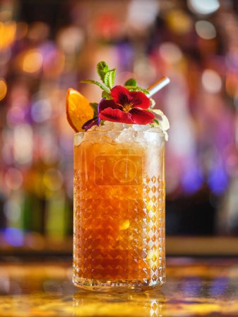 Téléchargez les photos : Verre de cocktail à boisson longue avec glaçons et décorations servis sur le comptoir dans un bar moderne sur fond flou avec bokeh - en image libre de droit
