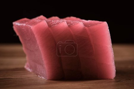 Téléchargez les photos : Tournage de tranches de thon rouge frais non cuites sur la table de cuisine - en image libre de droit