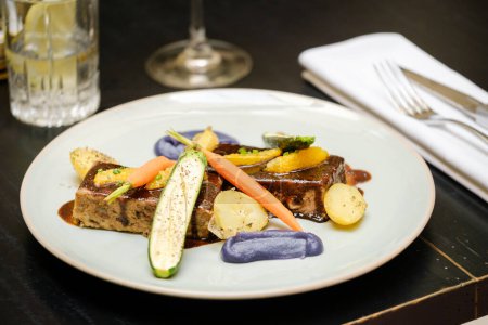 Téléchargez les photos : Grand angle d'assiette avec délicieux foie gras servi avec des légumes variés et garni de sauce sur la table au restaurant - en image libre de droit