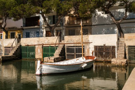 Foto de Velero blanco amarrado en el puerto de la ciudad costera con edificios de piedra y árboles verdes en el día de verano - Imagen libre de derechos