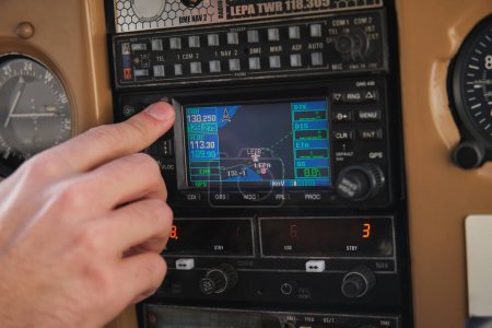 Téléchargez les photos : Recadrez le bouton-poussoir masculin méconnaissable de l'aviateur sur le panneau de commande tout en étant assis dans le cockpit d'un avion moderne - en image libre de droit