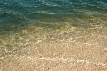 Photo for Full frame background of transparent clean rippling sea water washing wet sandy coast - Royalty Free Image
