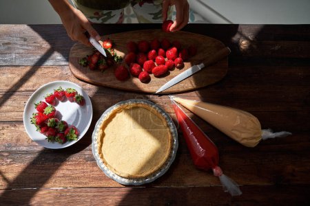 Photo for From above of  person preparing delicious cake and cutting fresh strawberries - Royalty Free Image