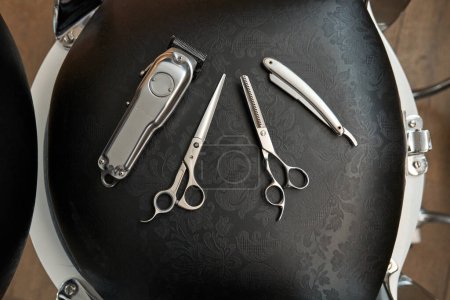 Foto de Vista superior de varios suministros de peluquería colocados en la silla negra en la barbería profesional - Imagen libre de derechos