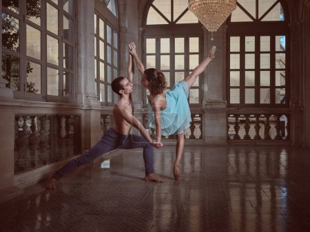 Téléchargez les photos : Vue latérale de la ballerine debout scindée et artiste torse nu se regardant pendant la danse dans la salle de bal - en image libre de droit