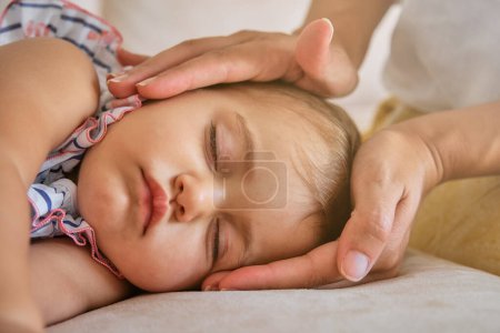 Photo for Crop unrecognizable mother touching sleeping cute little baby face with hands on sofa at home - Royalty Free Image