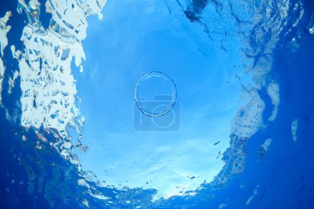 Foto de Desde abajo bajo el agua de anillo de aire que fluye en la superficie de agua cristalina transparente en la piscina en el día soleado - Imagen libre de derechos