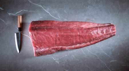 Téléchargez les photos : Tournage de morceaux de thon rouge frais non cuits sur la table de cuisine - en image libre de droit