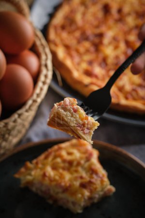 Photo for Soft focus of person eating tasty bacon and cheese quiche over table with eggs during lunch - Royalty Free Image