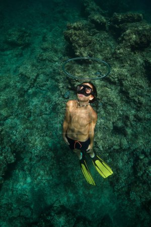 Foto de Cuerpo completo de niño sin camisa en máscara de snorkel y aletas nadando a través del anillo de burbujas en el mar profundo durante las vacaciones - Imagen libre de derechos