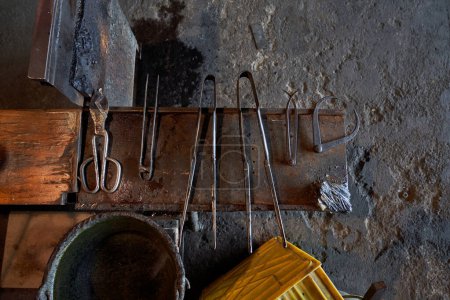 Photo for High angle of various glass making tools arranged on metal bench in workshop against weathered wall - Royalty Free Image