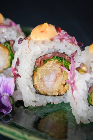 Téléchargez les photos : Gros plan de délicieux sushis japonais frais aux crevettes et sauce servis sur plaque de marbre avec fleur sur fond noir - en image libre de droit