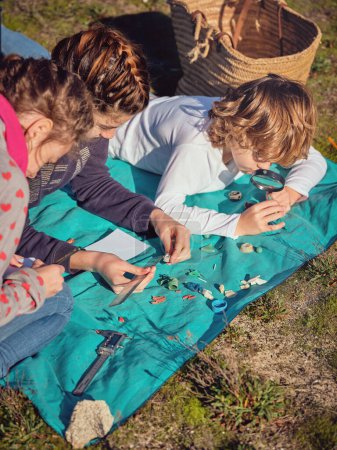 Foto de Desde arriba de los niños enfocados acostados en la manta azul en el suelo y observando y midiendo recogido basura y residuos de plástico - Imagen libre de derechos