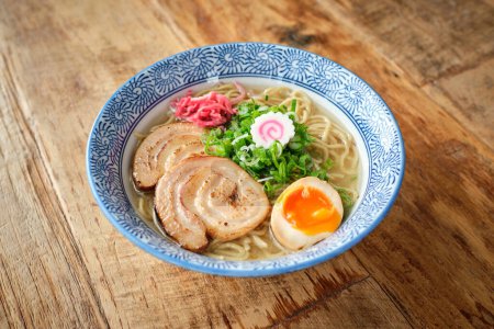 Photo for From above of yummy fresh ramen soup made with pork and noodles decorated with narutomaki served in bowl on wooden plate - Royalty Free Image