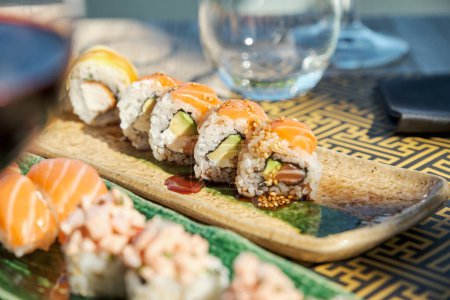 Foto de Primer plano de sushi fresco apetitoso servido en plato de cerámica con salsa y colocado en la mesa - Imagen libre de derechos