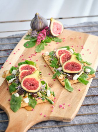 Photo for High angle of assorted sliced figs placed on crackers on wooden cutting board - Royalty Free Image