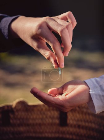 Photo for Crop unrecognizable person putting small piece of waste plastic into hand of preteen boy in sunny day - Royalty Free Image