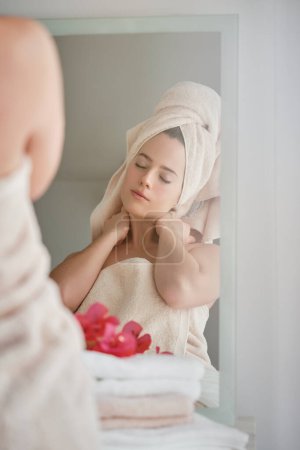 Foto de Mujer joven y tranquila con los ojos cerrados tocando el cuello y disfrutando del procedimiento en el baño por la mañana - Imagen libre de derechos