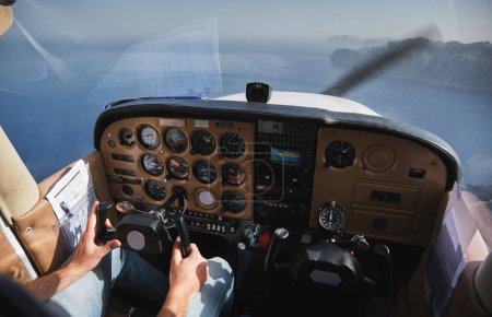 Foto de Crop aviador masculino anónimo dirección de los controles del avión mientras vuela sobre el mar azul calma en tiempo soleado - Imagen libre de derechos