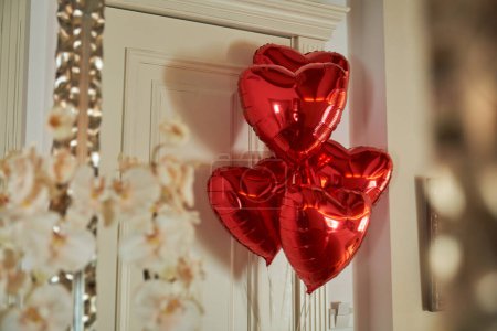 Téléchargez les photos : Ballons rouges brillants en forme de coeur décorant la porte d'entrée de la suite de luxe de l'hôtel en vacances - en image libre de droit