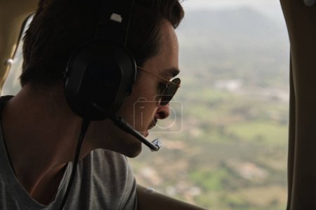 Photo for Stock photo of happy man wearing aviation headset enjoying light aircraft tour and looking through the window. - Royalty Free Image