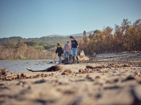 Foto de Grupo de niños voluntarios que buscan y recogen basura y desechos plásticos en el agua del río y en la costa - Imagen libre de derechos