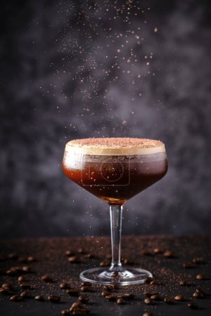 Foto de Delicioso cóctel decorado con chocolate rallado en la campaña coupé vidrio colocado en la mesa negra entre granos de café aromáticos dispersos en la barra - Imagen libre de derechos