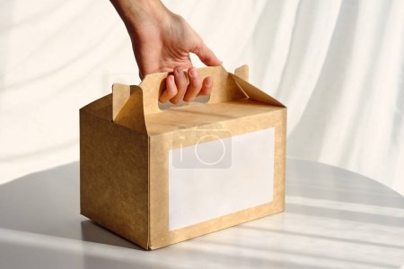 Téléchargez les photos : Grand angle de récolte femelle prenant boîte en carton avec achat de table blanche - en image libre de droit