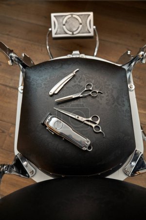 Photo for From above of different hairdressing tools placed on black leather chair in professional barbershop - Royalty Free Image