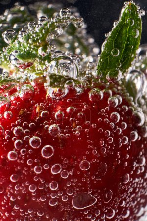 Téléchargez les photos : Gros plan fraise entière fraîche recouverte de bulles flottant dans de l'eau claire et transparente - en image libre de droit