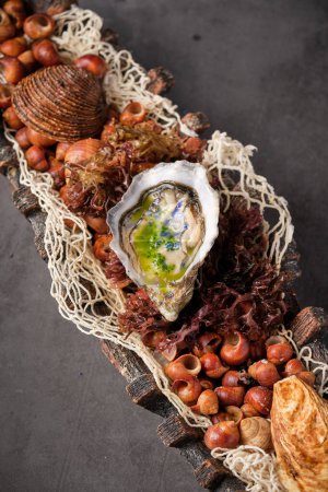 Foto de Desde arriba de ostra sabrosa en cáscara servida en plato con diversos ingredientes de mariscos en restaurante - Imagen libre de derechos