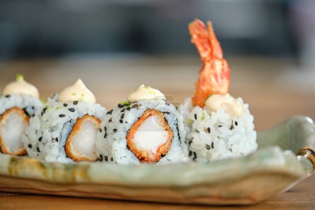 Photo for Appetizing sushi rolls made of rice shrimp and sesame served on ceramic tray and decorated with shrimp - Royalty Free Image