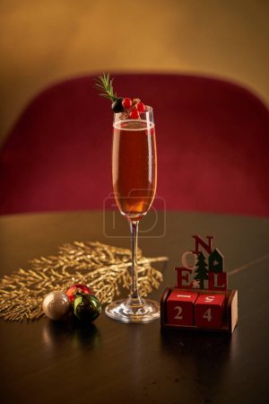 Foto de Copa de champán decorado con bayas servidas en la mesa con bolas de Navidad y cubos de madera con fecha del 24 de diciembre - Imagen libre de derechos