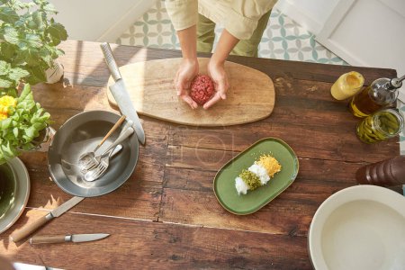 Photo for From above of crop anonymous female cooking steak tartar on wooden cutting board in light kitchen - Royalty Free Image